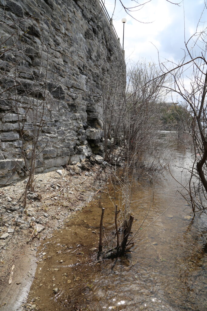 Stone retaining wall against riverbank.