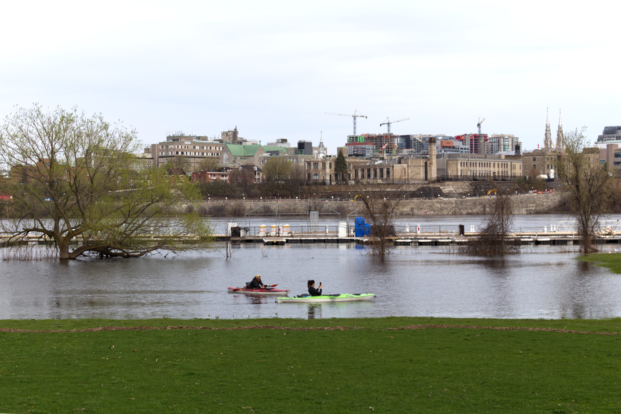 view of buildings in background with river and kayakers in foreground.